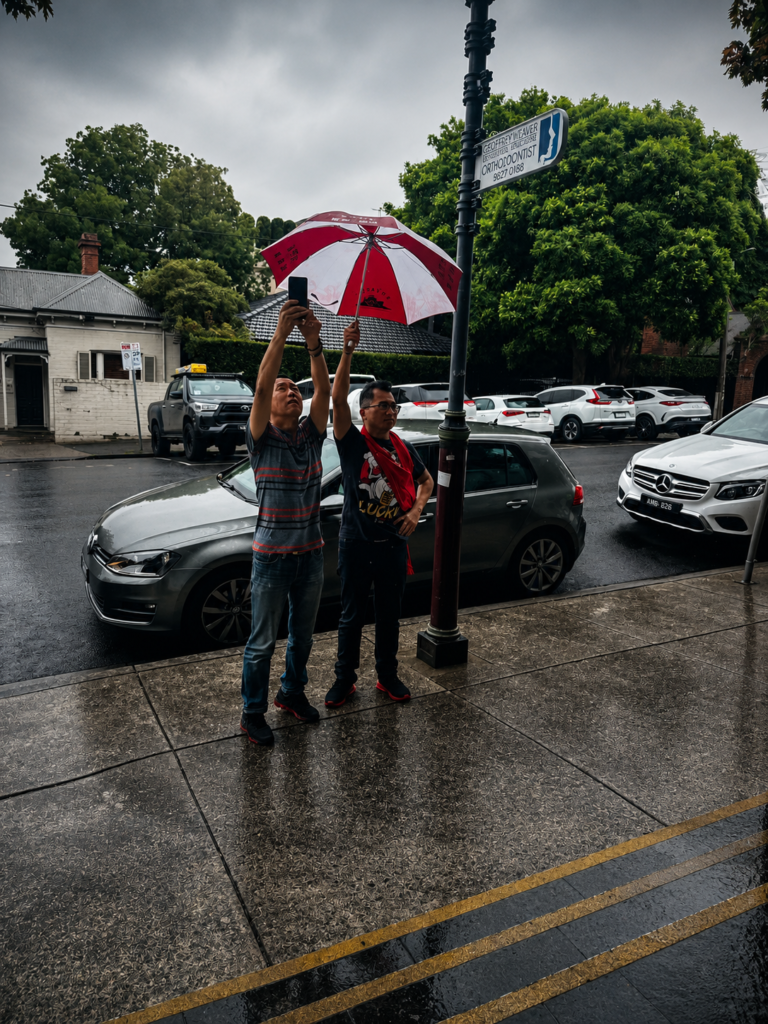 While everyone rushed under cover, two volunteers stayed outside in the rain, making sure every member could fit into the shot.